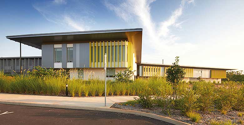 Cantilevered roofs sitting lantern-like atop the weightiness of a concrete block work-base, MacKillop Catholic College in the Northern Territory, roofing, wall cladding, soffits and flashing made from COLORBOND® steel in the colours Windspray®, Jasper®, and Shale Grey™