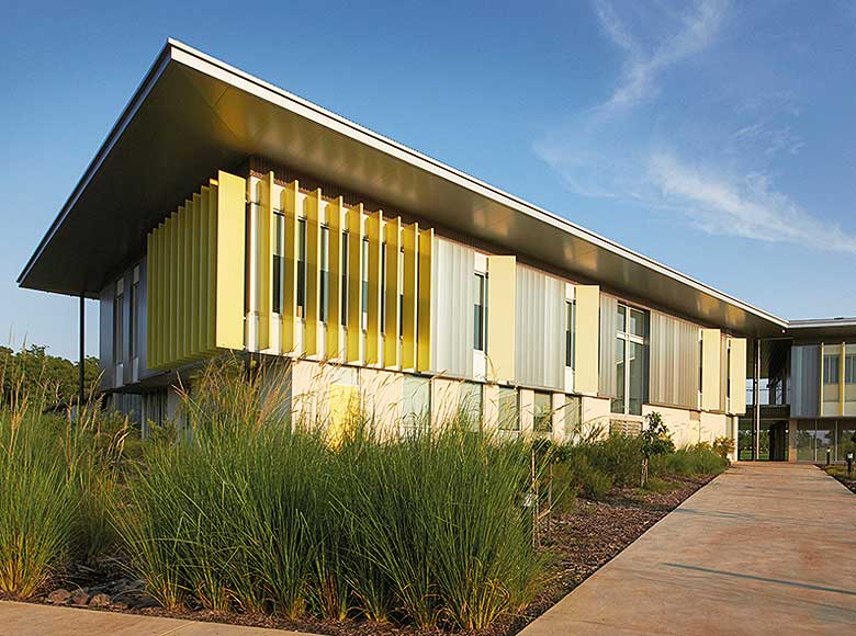 Cantilevered roofs sitting lantern-like atop the weightiness of a concrete block work-base, MacKillop Catholic College in the Northern Territory, roofing, wall cladding, soffits and flashing made from COLORBOND® steel in the colours Windspray®, Jasper®, and Shale Grey™